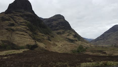 Cinematic-shot-of-a-couple-of-hikers-contemplating-the-majestic-mountains-in-Glencoe-and-mesmerized-by-Scottish-scenery