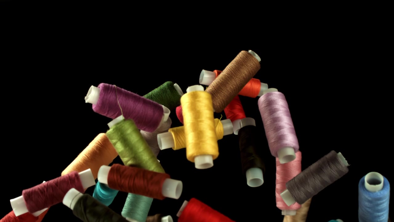 Colorful Spools of Thread Falling on Black Background