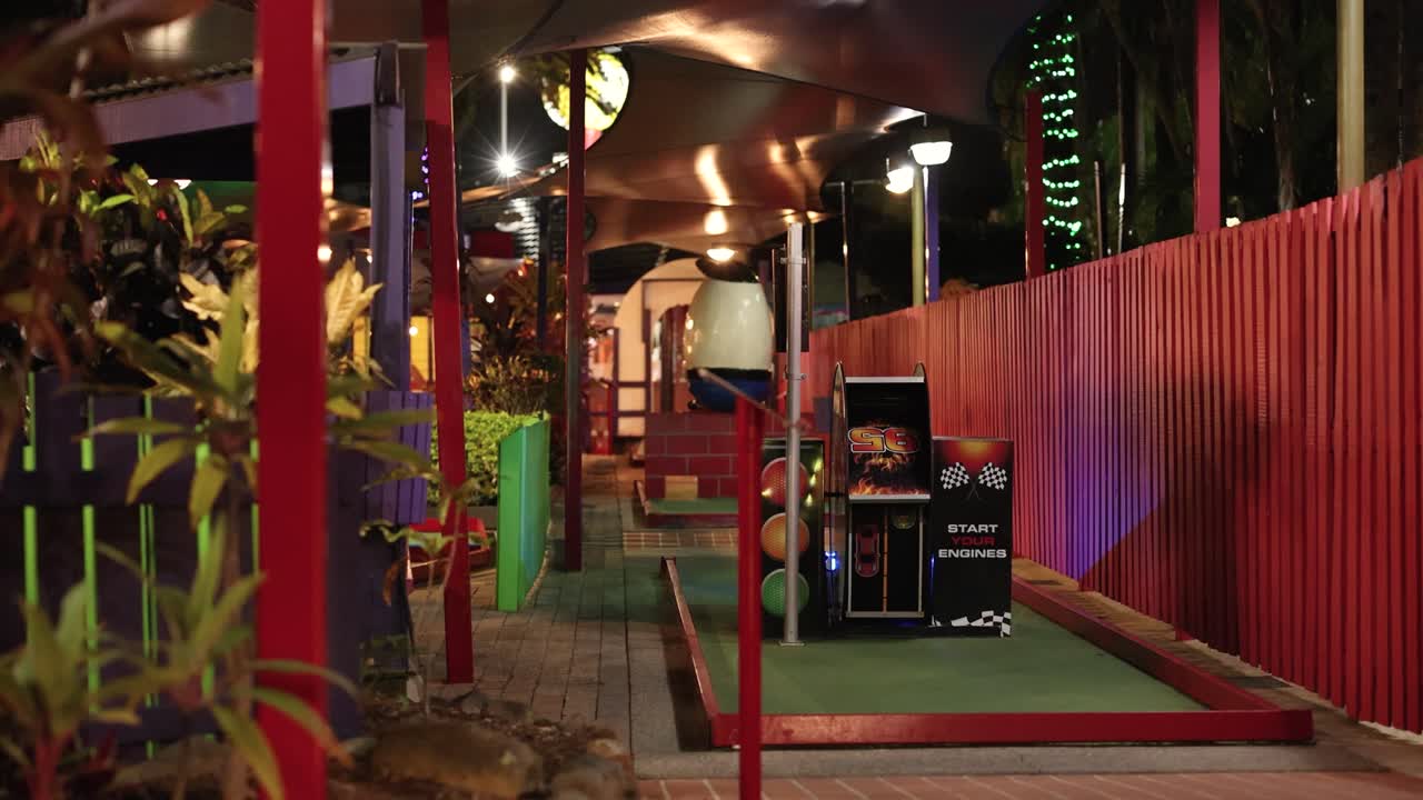 A vibrant mini golf course with neon lights and an arcade machine, creating a playful and colorful atmosphere