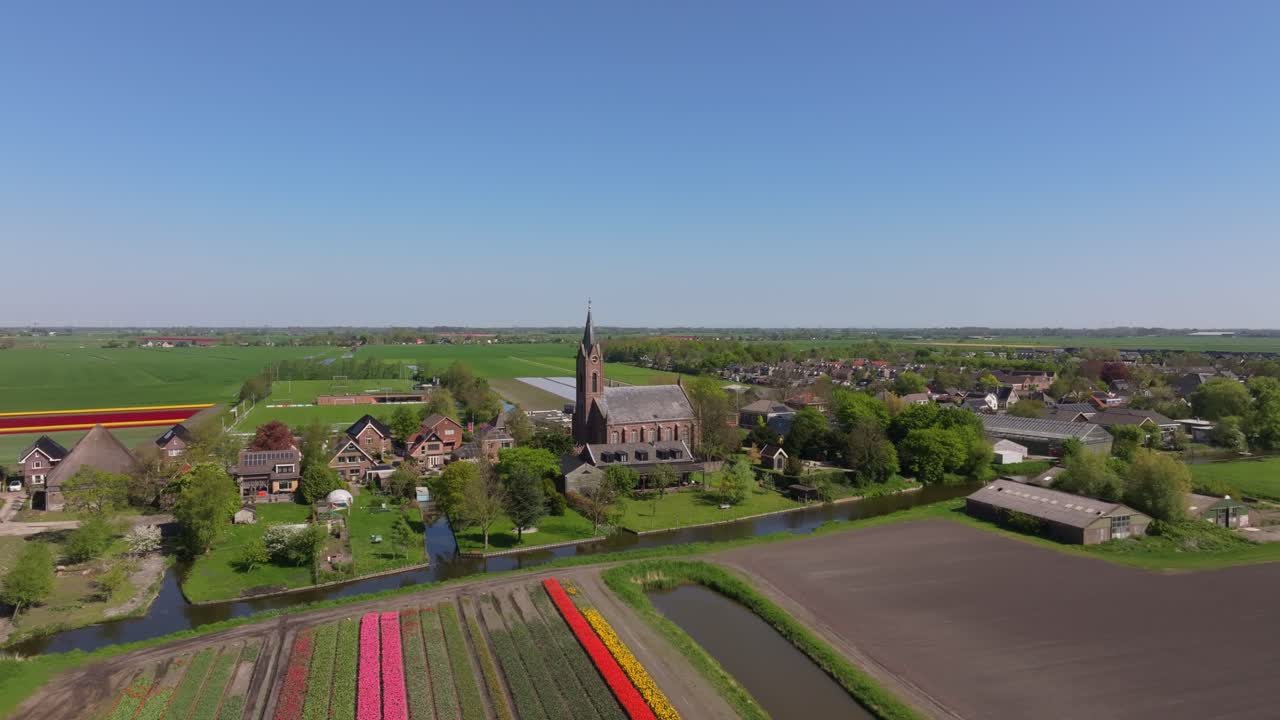 Luchtfoto van levendig tulpenlandschap met dorp Berkhout op de achtergrond.