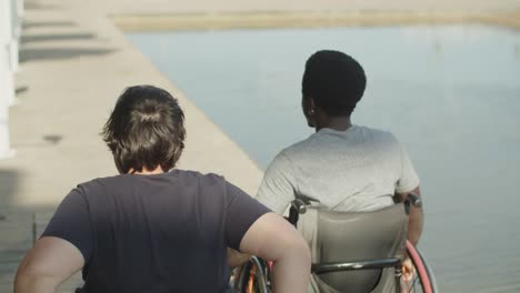 rear view of male and female friends using wheelchairs walking