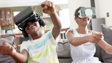 happy african american brother and sister using vr headsets on sofa, slow motion