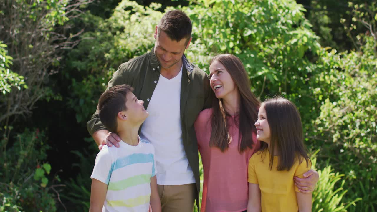 retrato de una familia caucásica sonriendo mientras están juntos en el jardín