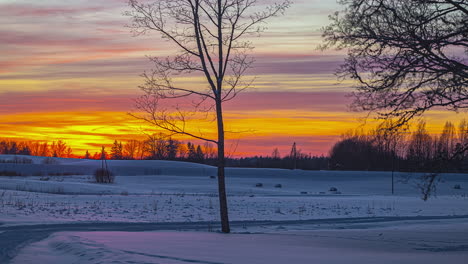 Fire-sunset-with-vivid-sky-in-snowy-landscape,-clouds-moving