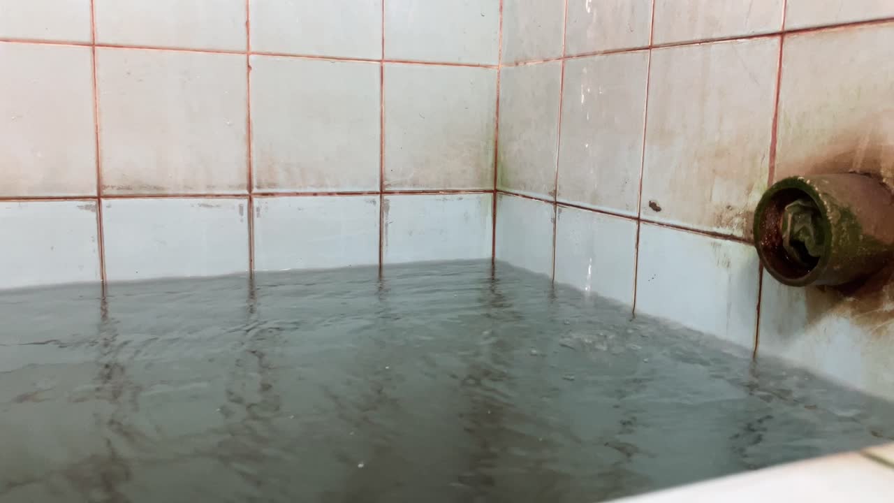 약간 딱딱한 푸른색 세라믹 물통의 수도꼭지에서 물이 떨어지고 있어요