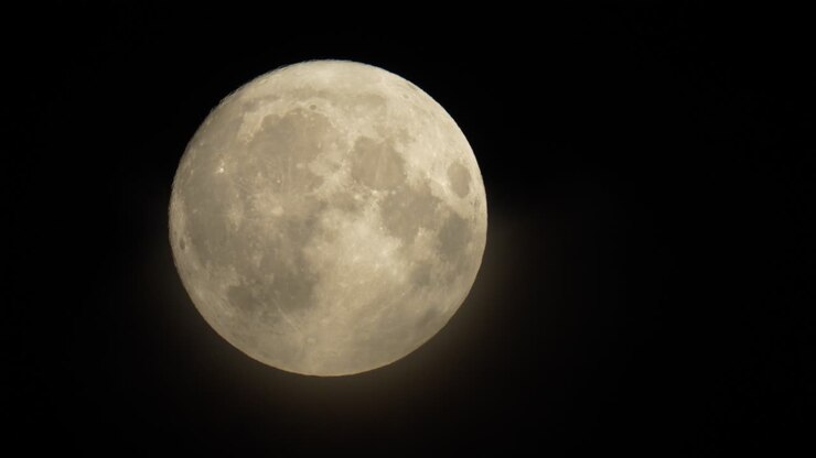 Véus de nuvens tênues cruzam a face da lua cheia nascente.