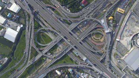 Vista-Aérea-Del-Cruce-De-Carreteras-Con-Tráfico-Urbano-Intenso-Acelerando-En-La-Carretera