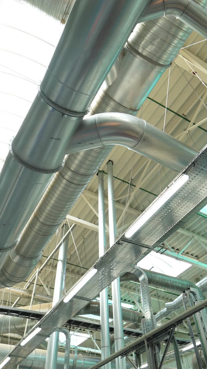 Pipes of the ventilation system are located on the ceiling of plant with the production of parquet. Camera motion to left Vertical video