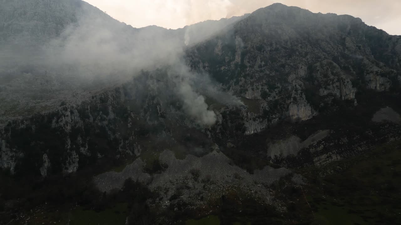 Mountain range with rising thick smoke under clear sky
