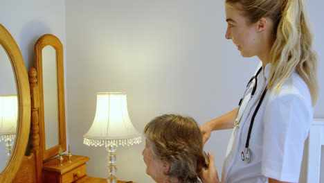 médico peinando el cabello de una mujer mayor en el tocador 4k