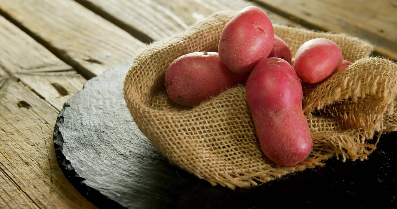 Cursor pairando perto de uma travessa de ardósia, distintivos começando a se empilhar em torno de batatas vermelhas para marketing de alimentos.