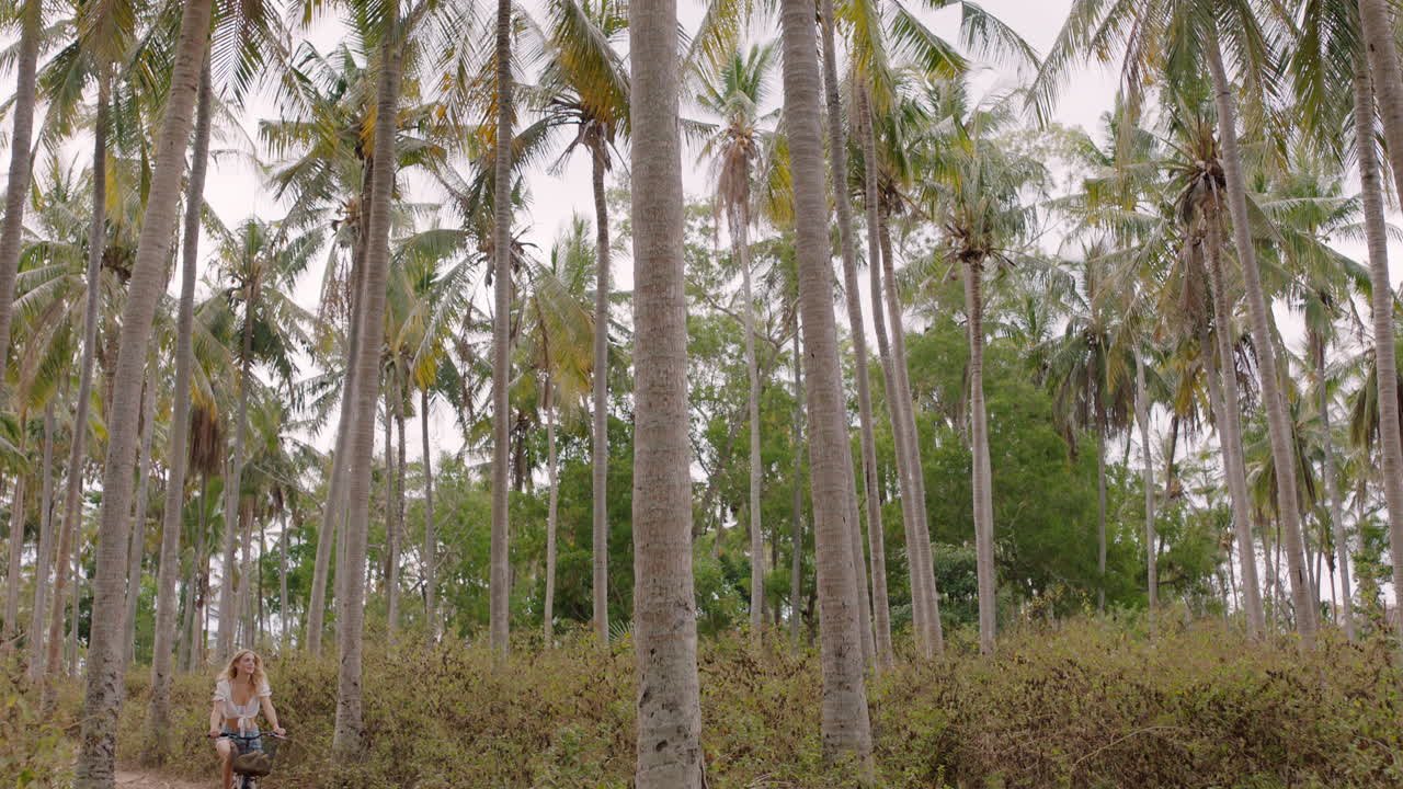 mujer en bicicleta explorando una isla tropical chica en bicicleta disfrutando de un hermoso bosque de palmeras 4k