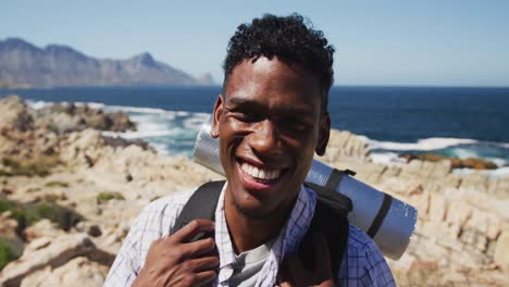 Portrait-of-african-american-man-exercising-outdoors-hiking-in-countryside-on-a-coast