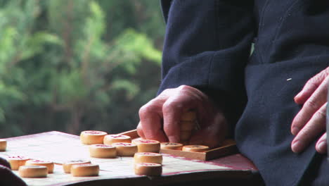 los ancianos juegan mah jong o damas chinas en un parque en china mientras los transeúntes observan