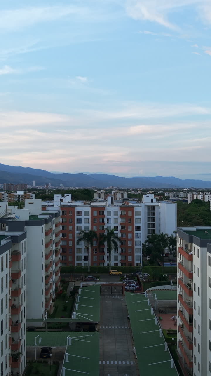 Aerial shot showcasing Valle del Lili's residential buildings with a backdrop of mountains under a pastel sky dynamic movement captivating scenes cinematic quality