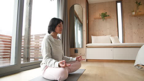 woman meditating on yoga mat in cozy wooden room, finding inner peace, copy space