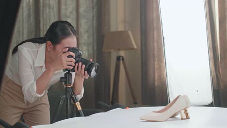 asian female photographer checking the photos of women's shoes after taking them in home studio