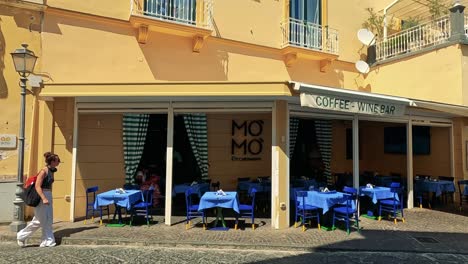 person walks by a sunny italian cafe