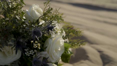 Nahaufnahme-Einer-Weißen-Rose-Mit-Distelhochzeitsstrauß,-Der-Im-Wind-Weht,-Platziert-Auf-Dem-Sand-Der-Kleinen-Sahara-sanddünen-In-Joab,-Ut