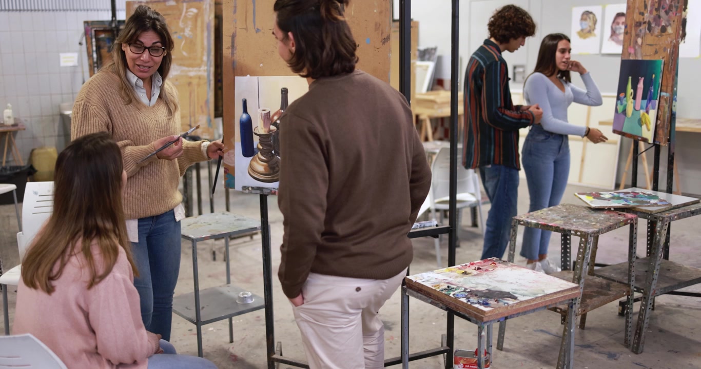 Studenti umění diskutující o obrazech v kreativní ateliérové učebně