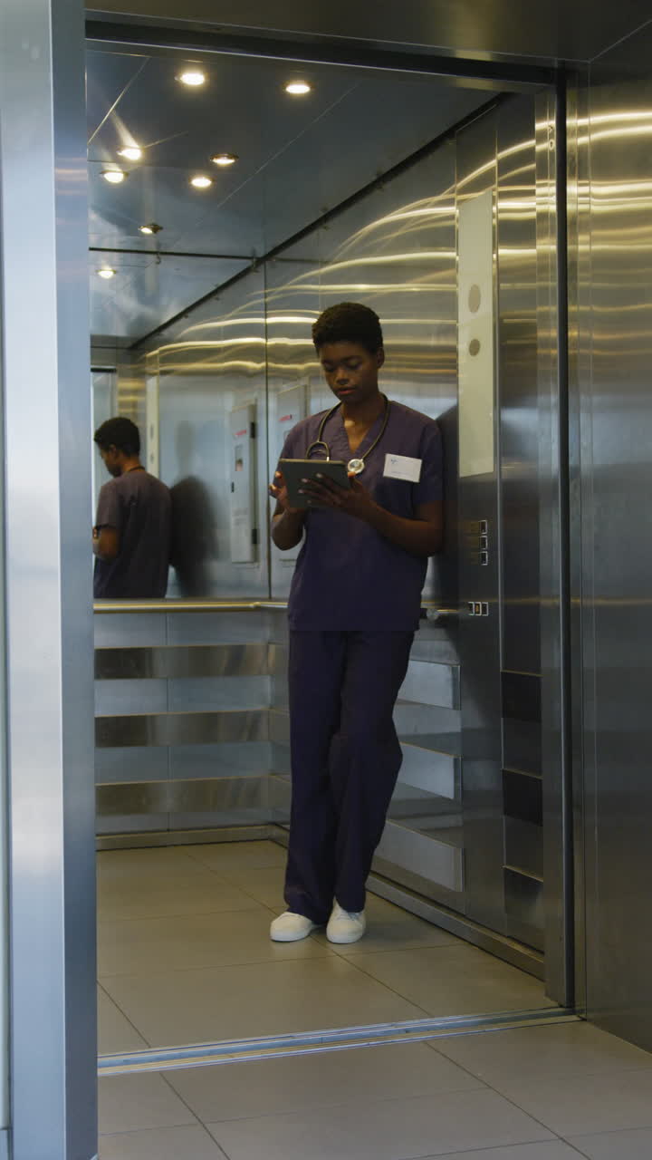video vertical de una mujer médica afroamericana usando una tableta en el hospital