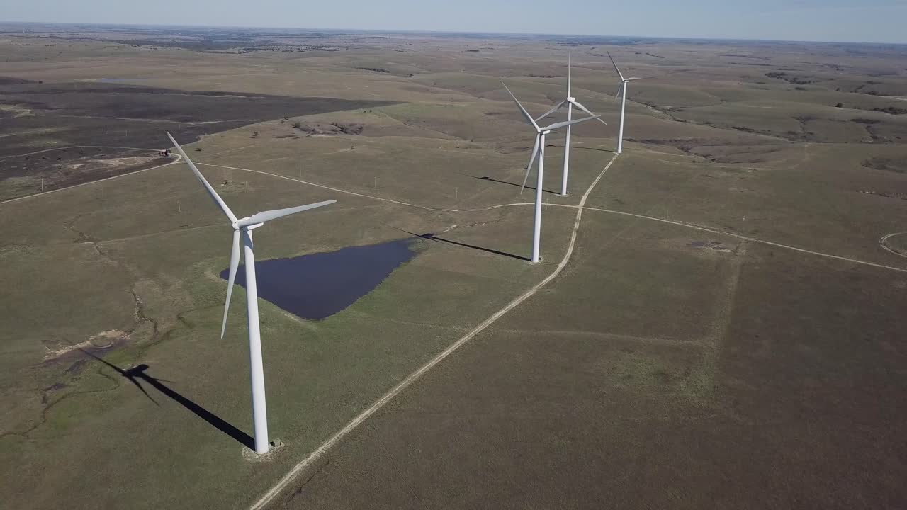Aerial drone footage of windmills during summer over farm fields in Kansas, United States