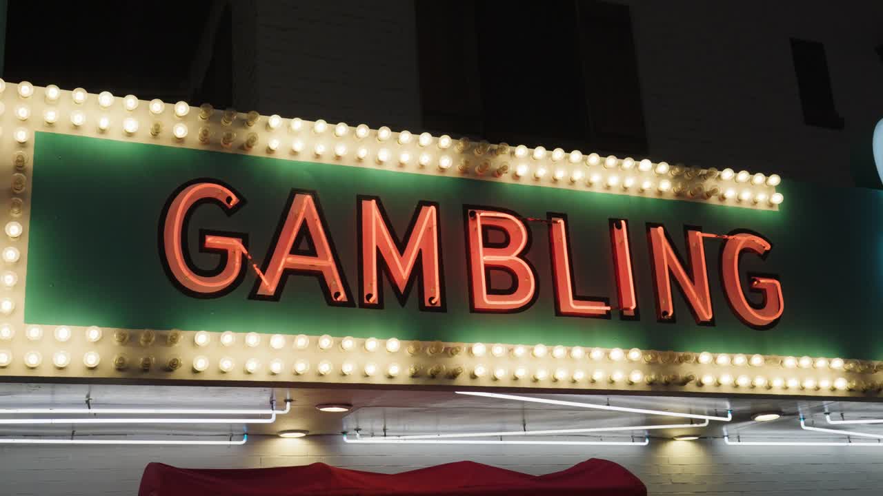 A green and gold sign reads &amp;quot;Gambling&amp;quot; using neon lights in a flickering pattern and red neon tube letters in the old town Fremont district of Las Vegas