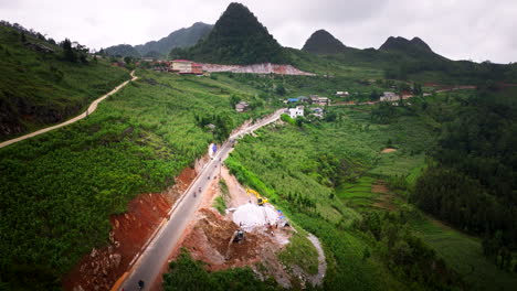 aerial shot of the ha giang loop in vietnam, showcasing winding roads and motorbikes and lush green mountains