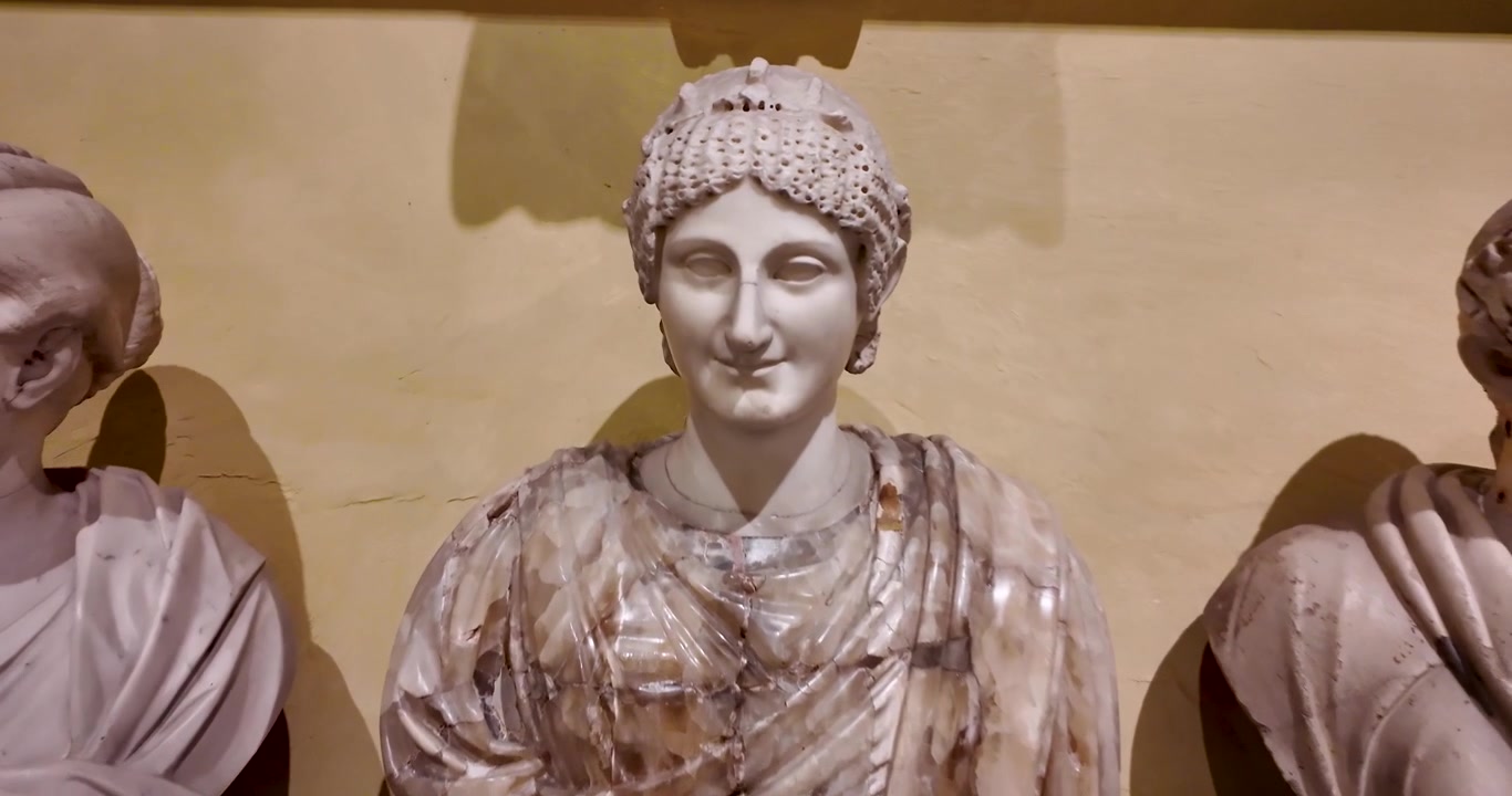 Movimento di macchina attraverso una collezione di antichi busti ritratto romani e frammenti scolpiti esposti all'interno del Museo Chiaramonti presso i Musei Vaticani.