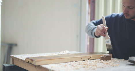 hombre pintando tablero de madera cepillado 1
