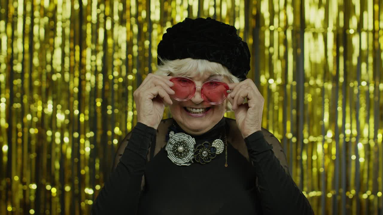 Lovely senior old woman touching red sunglasses and winking playfully, flirting and blinking eye