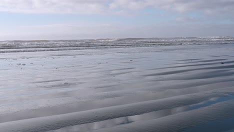 waves gently roll across a serene coastal beach under soft light and scattered clouds