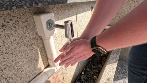 sequence of handwashing at an outdoor water tap.