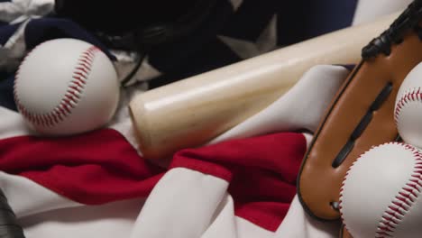 overhead baseball still life with catchers mitt on american flag as person picks up bat and ball