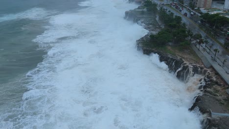 enormes olas de ciclones tropicales aplastando e inundando la costa de una ciudad - vista aérea