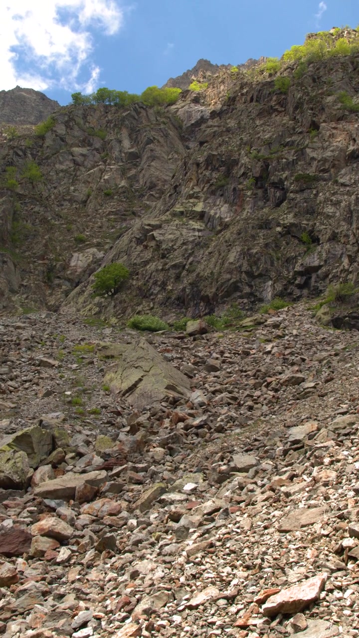 Una panoramica verticale della telecamera si sposta da un ghiaione roccioso fino a una cima di montagna.