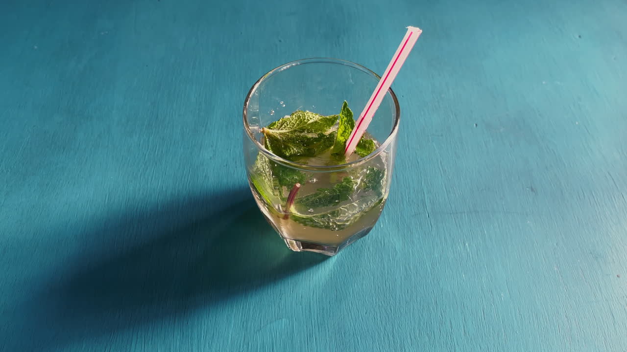 Lasi jäämojitoa vihreillä mintunlehdillä ja sitrushedelmillä.