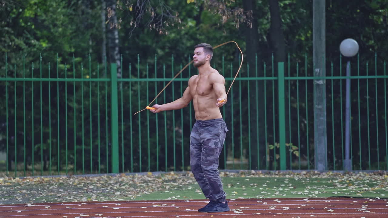 Man exercising with jumping rope. Yong handsome fit man jumping rope on stadium