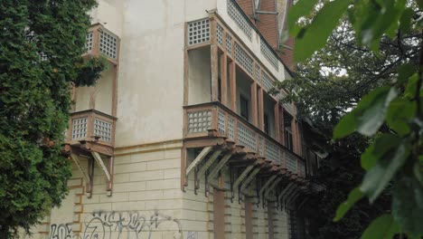 panning-up toma de un edificio abandonado visto a través de las hojas verdes