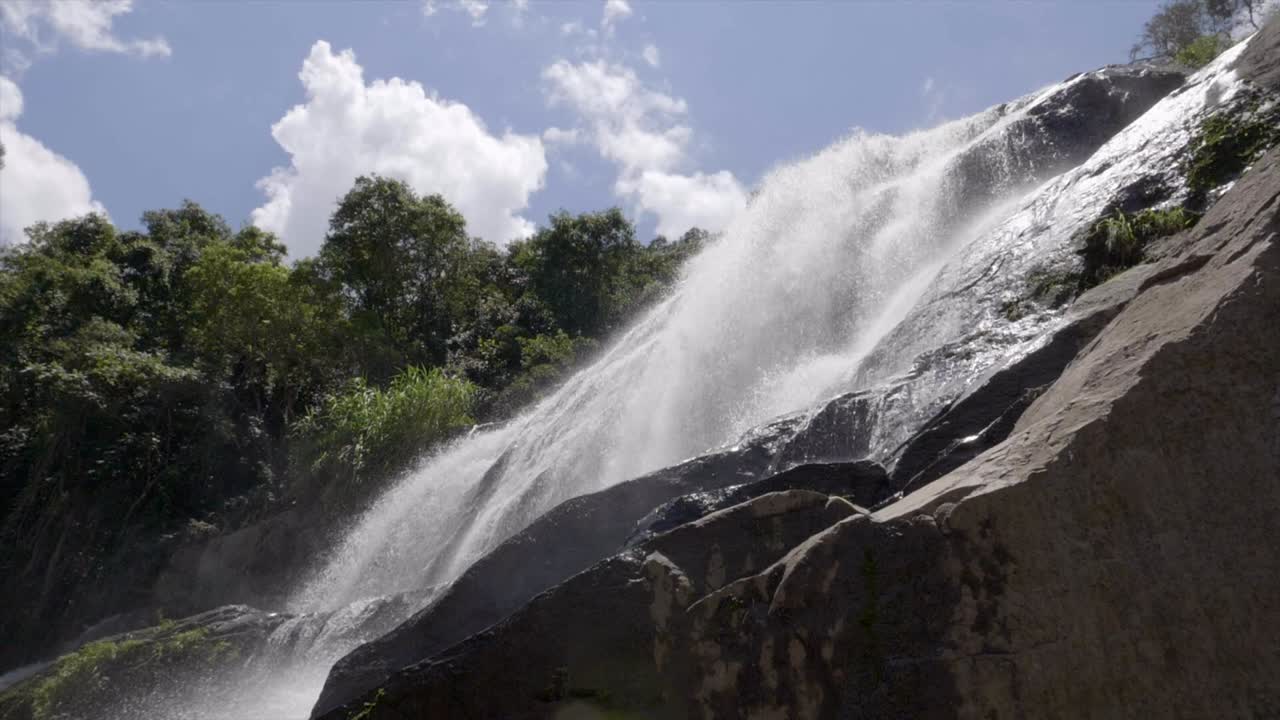 aguas en cascada a cámara lenta que corren de la cascada de terreno rocoso vista desde abajo