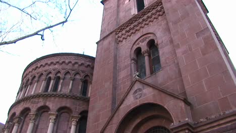 the camera pans up for a wormseye view of the facade of a red stone church to focus on ornamentation