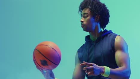 video of biracial male basketball player spinning ball on green background