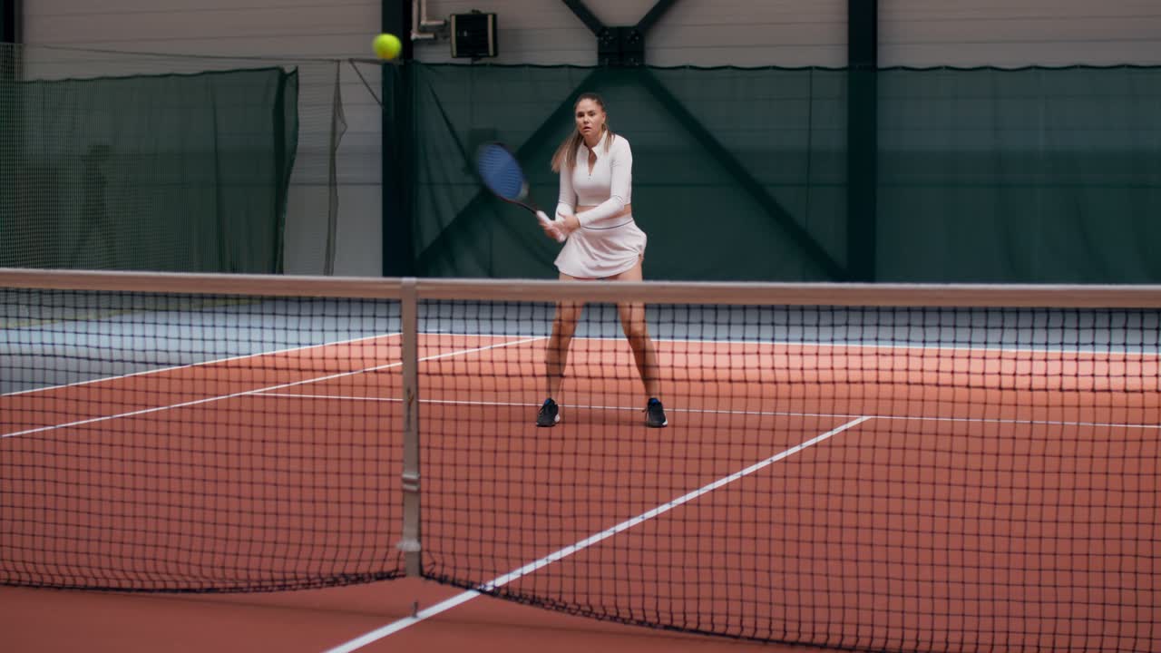 A woman playing tennis on an indoor court