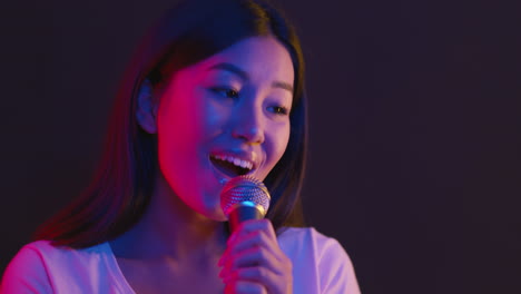 woman singing into a microphone with neon lights