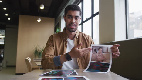 Mixed-race-businessman-having-a-video-chat-going-through-paperwork-modern-office