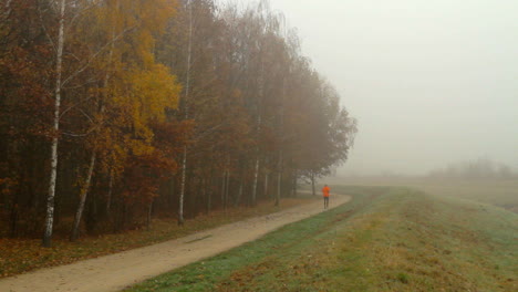 Ein-Mann-Joggt-Und-Ein-Radfahrer-Fährt-Am-Frühen-Morgen-Auf-Einem-Nebligen-Stadtparkweg