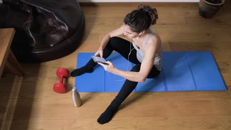 smiling sportswoman using smartphone at home