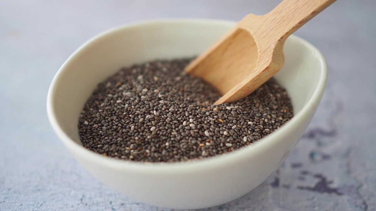 Semi di chia in una ciotola bianca con un cucchiaio di legno