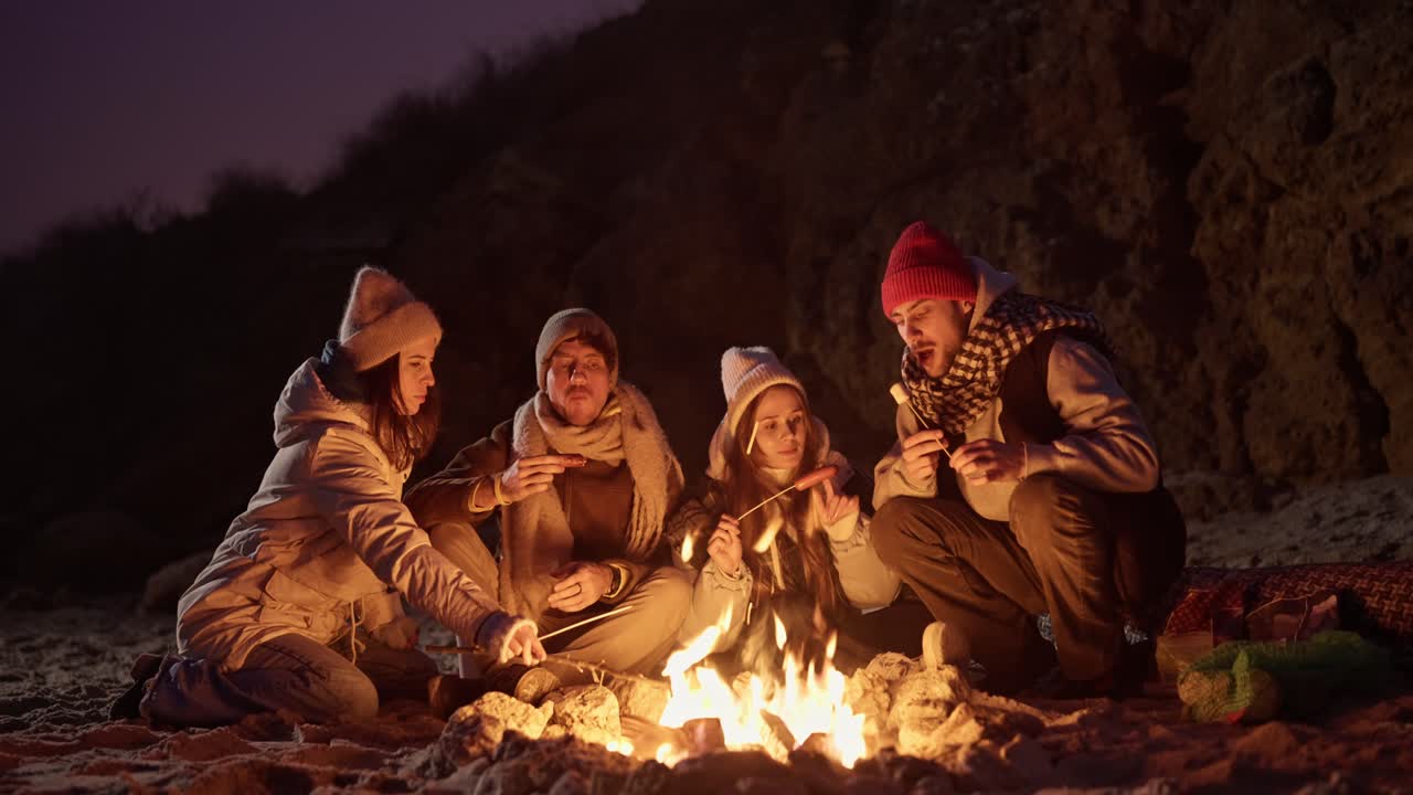 밤 에 해변 에서 불 을 피우고 있는 친구 들