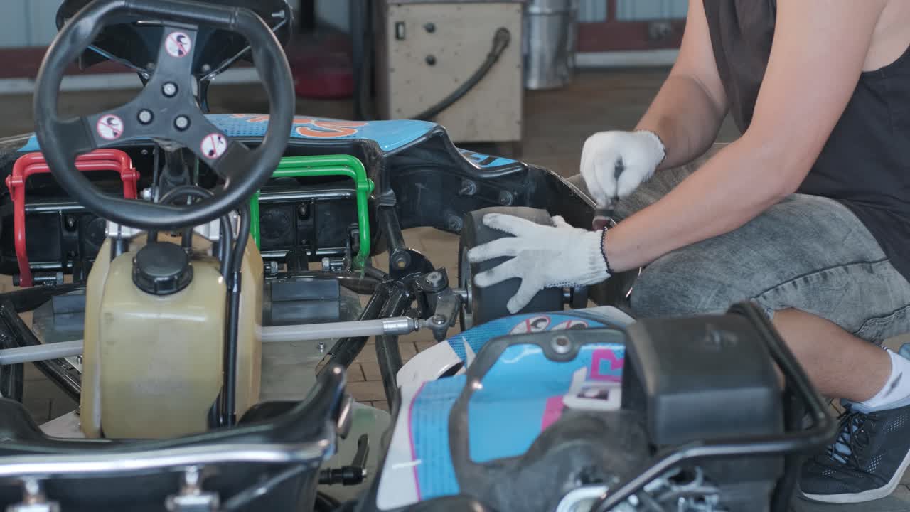 el mecánico del servicio de carreras de go kart cambia las ruedas